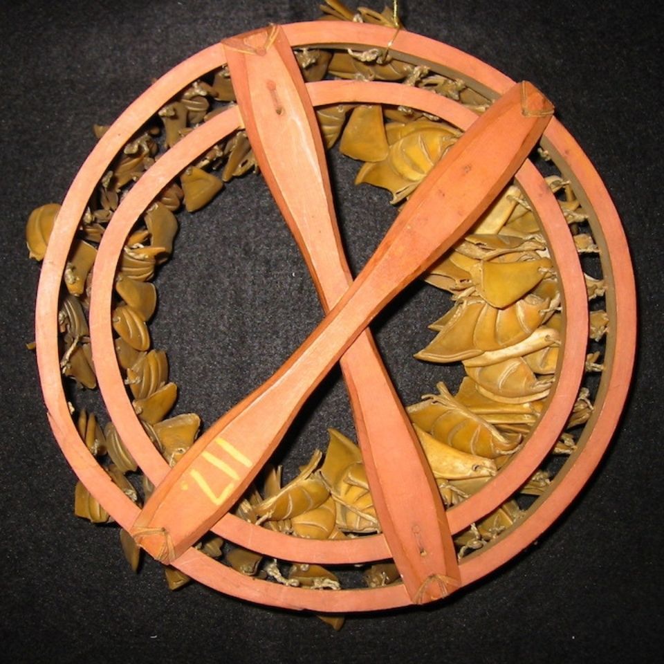 Drawing of a puffing beak rattle, with beaks lashed to two circular hoops, ties to a long narrow handle.